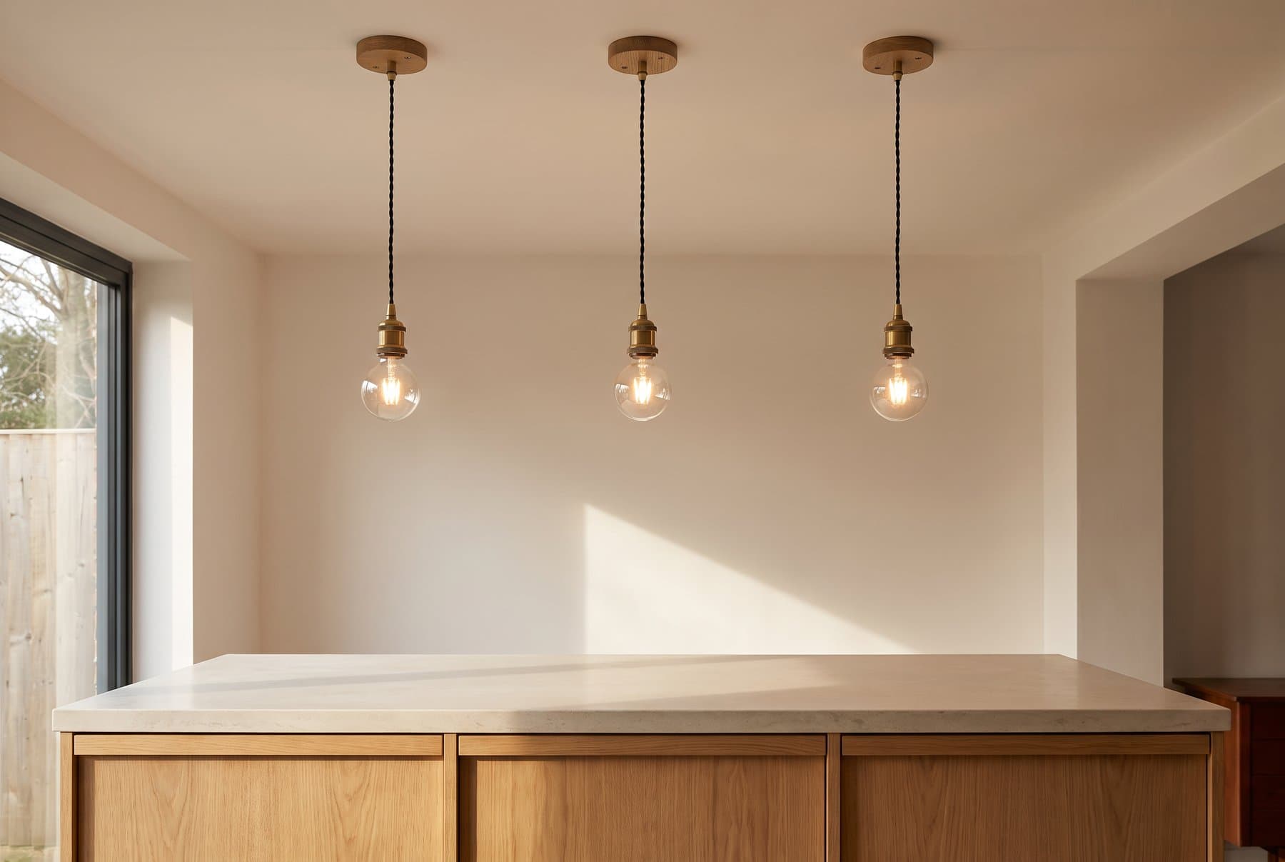 Three pendant lights on turned oak ceiling roses over a kitchen island