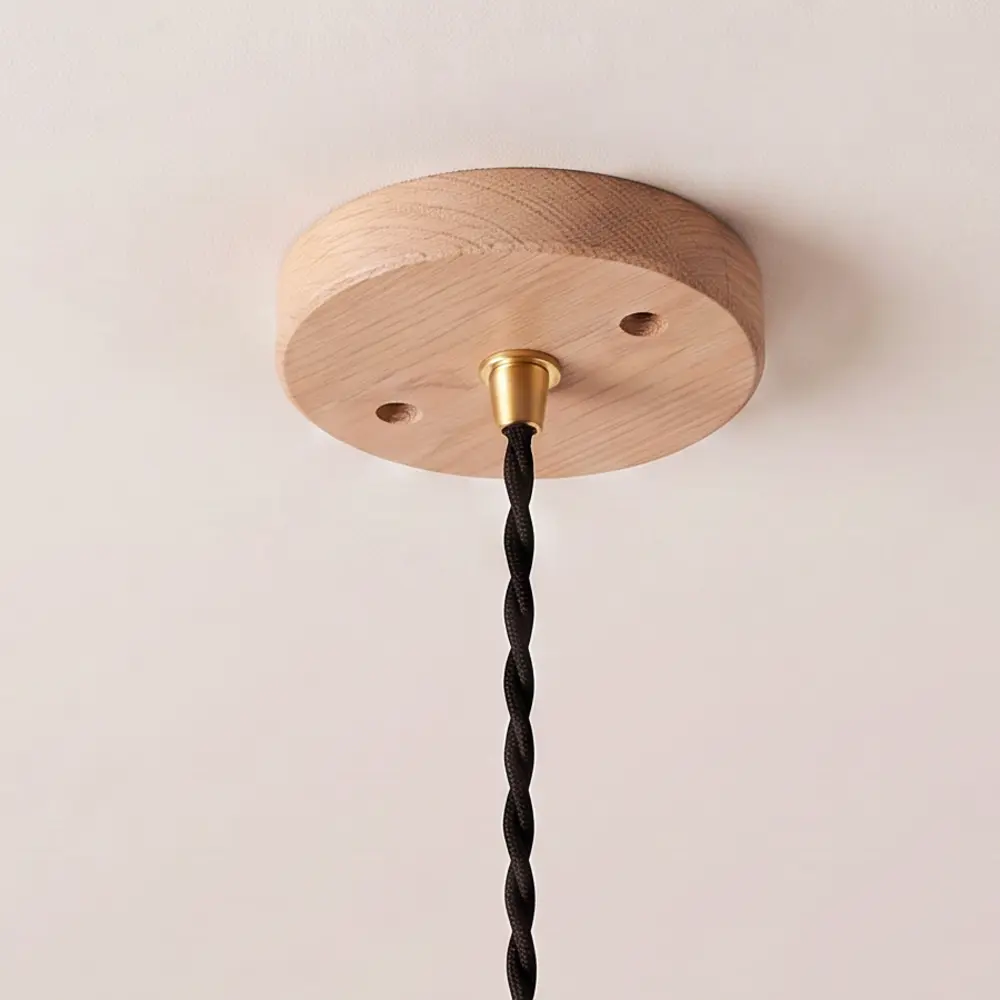 Close detail of the turned natural oak ceiling rose with black twisted fabric flex hanging from it