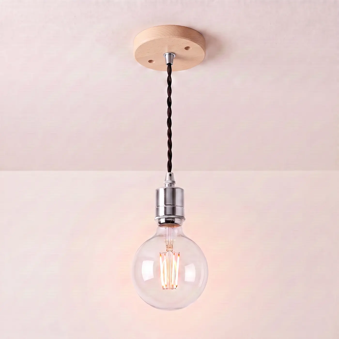 Pendant light with a turned beech ceiling rose, black twisted fabric flex and a chrome bulb holder, lit with a clear globe filament bulb