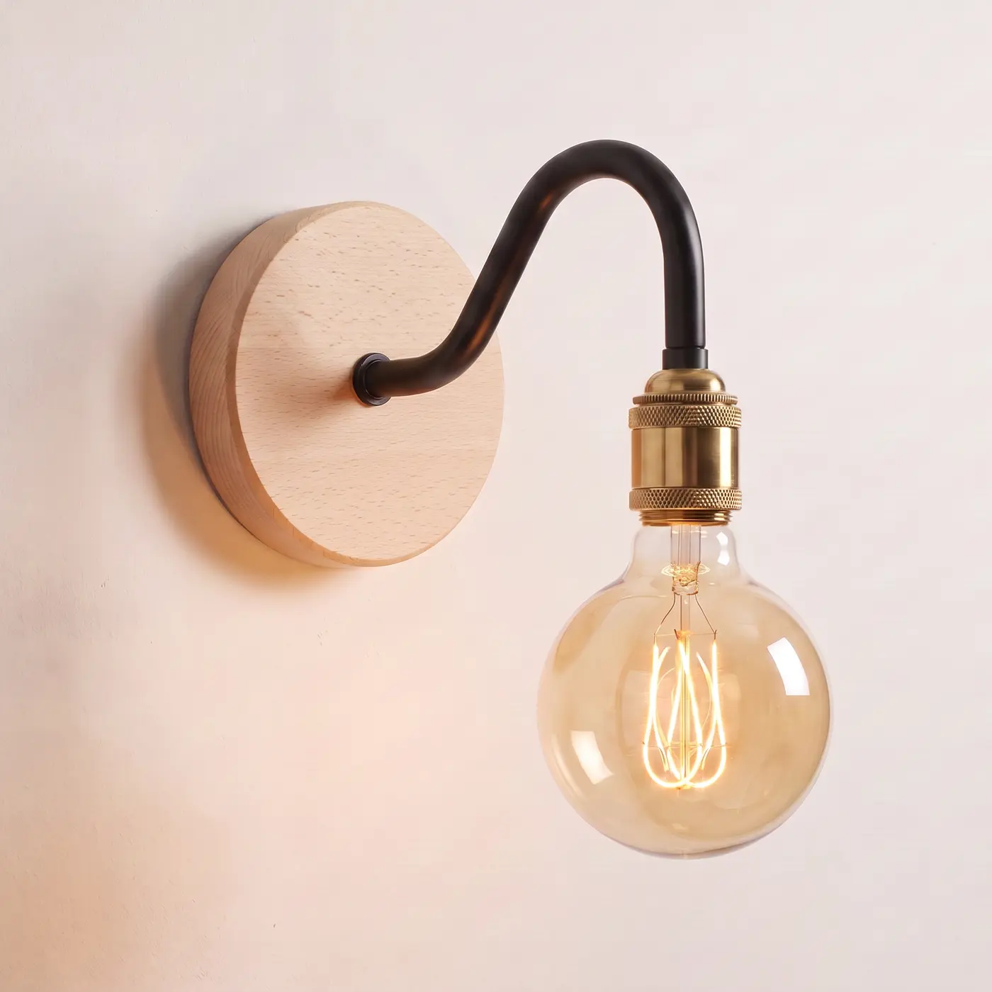 Swan neck wall light with a beech back plate, black swan neck arm and brass bulb holder, lit with a globe filament bulb