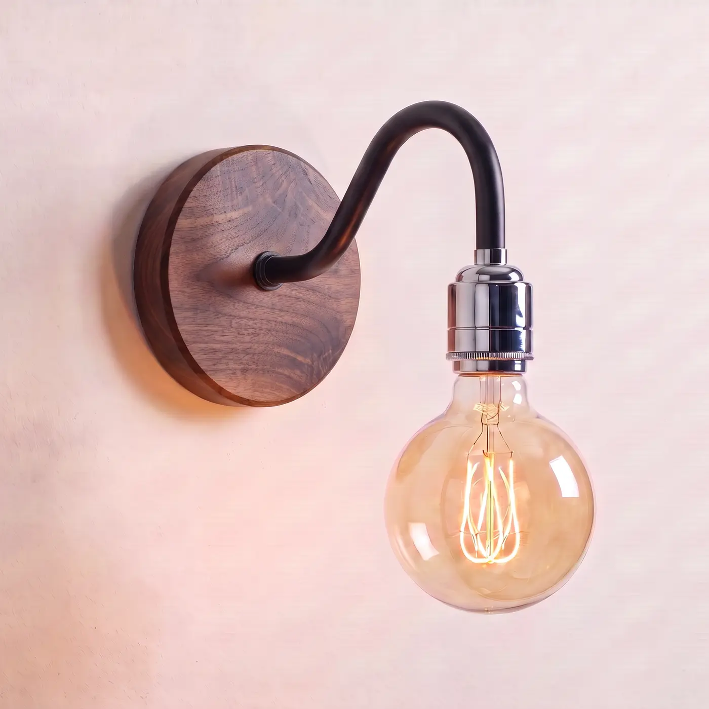 Swan neck wall light with a walnut back plate, black swan neck arm and chrome bulb holder, lit with a globe filament bulb