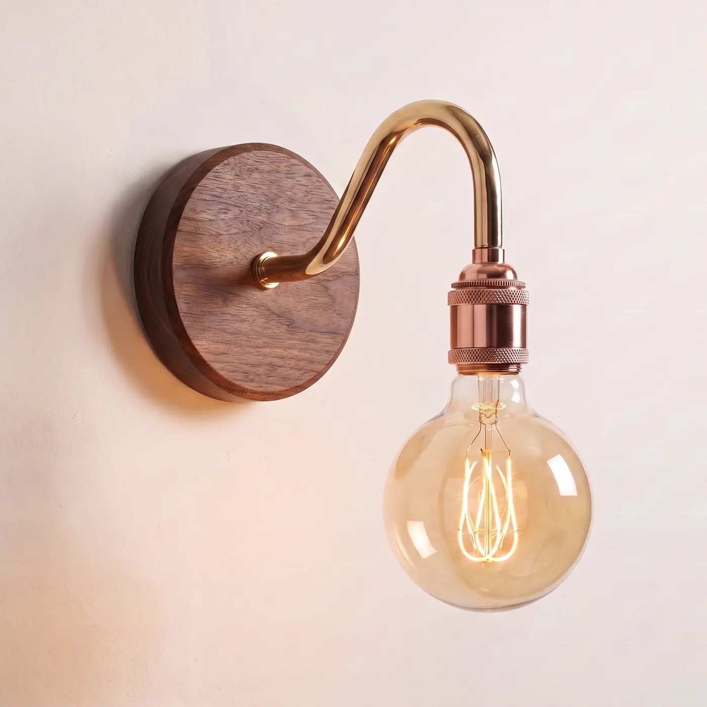 Swan neck wall light with a walnut back plate, brass swan neck arm and copper bulb holder, lit with a globe filament bulb