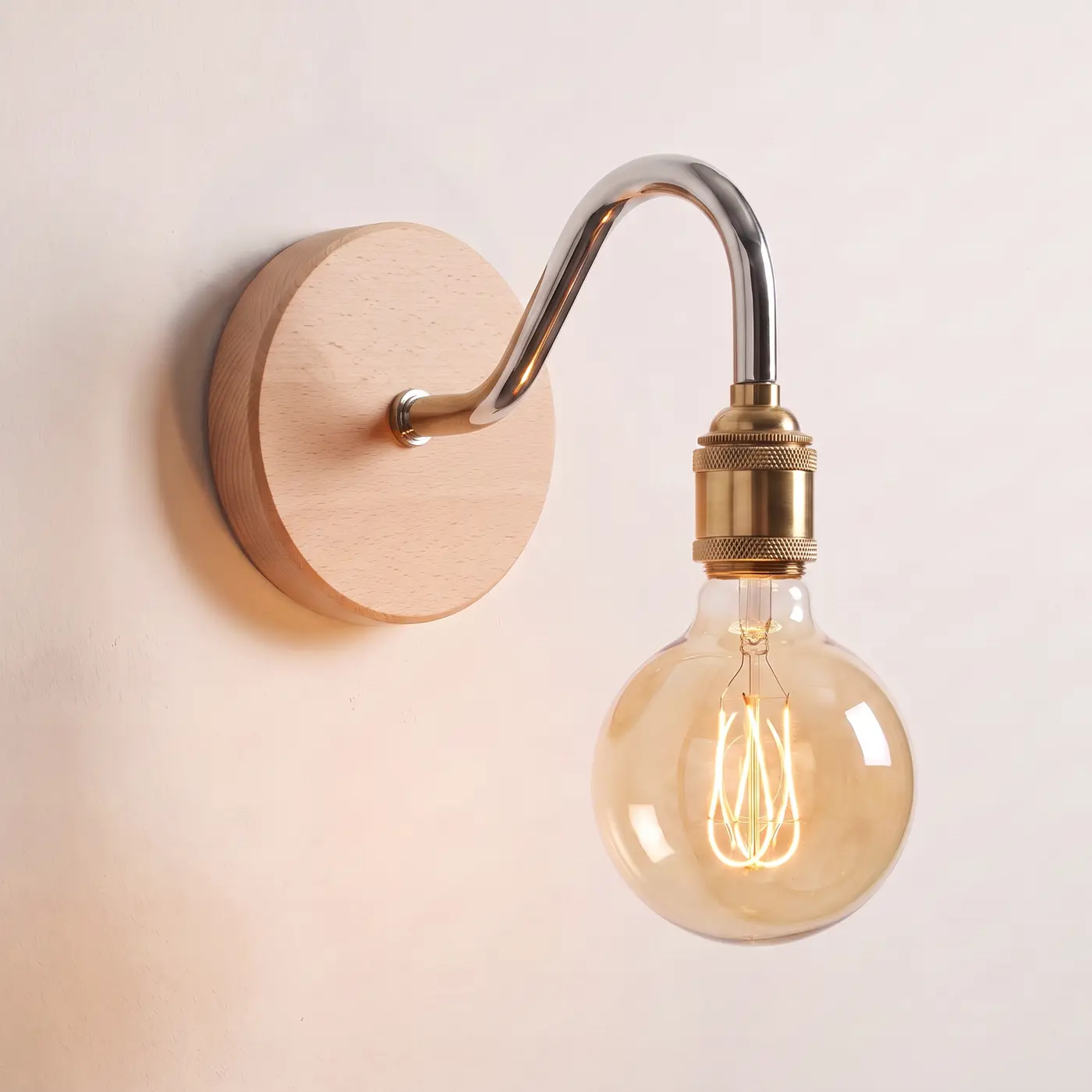 Swan neck wall light with a beech back plate, chrome swan neck arm and brass bulb holder, lit with a globe filament bulb