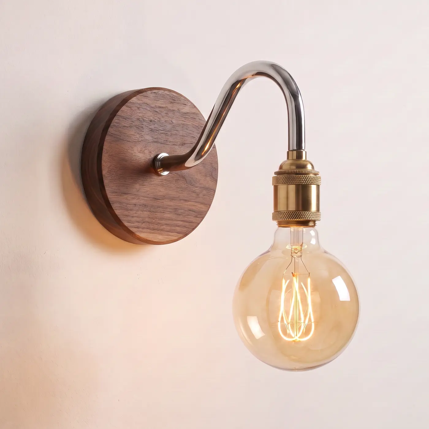 Swan neck wall light with a walnut back plate, chrome swan neck arm and brass bulb holder, lit with a globe filament bulb