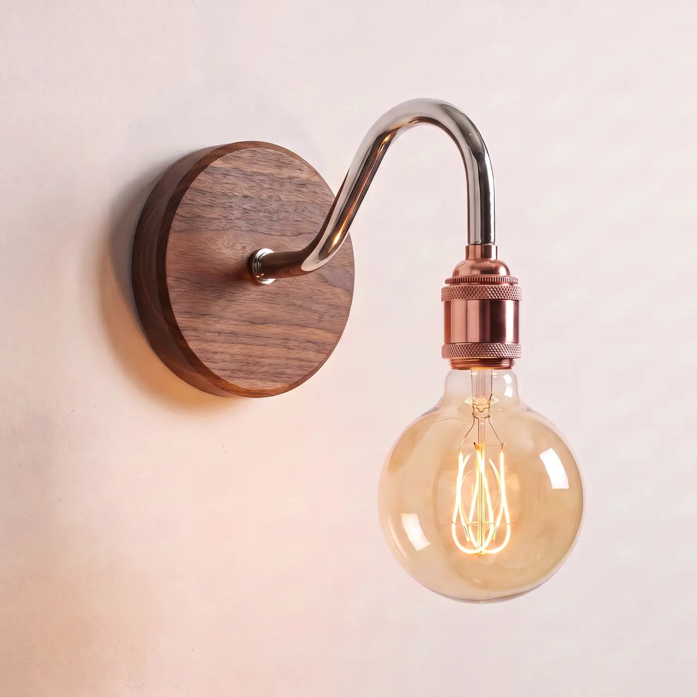 Swan neck wall light with a walnut back plate, chrome swan neck arm and copper bulb holder, lit with a globe filament bulb