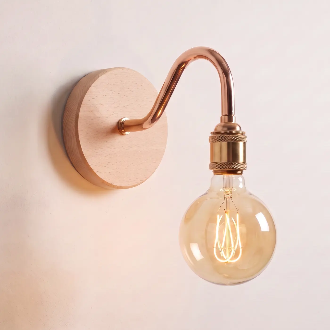 Swan neck wall light with a beech back plate, copper swan neck arm and brass bulb holder, lit with a globe filament bulb