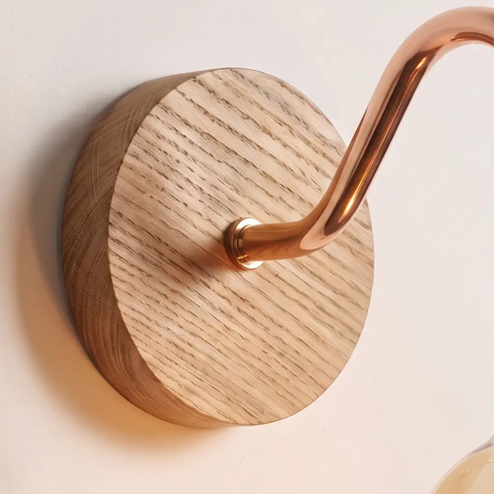 Close detail of the turned natural oak back plate and the copper collar where the swan neck arm meets it