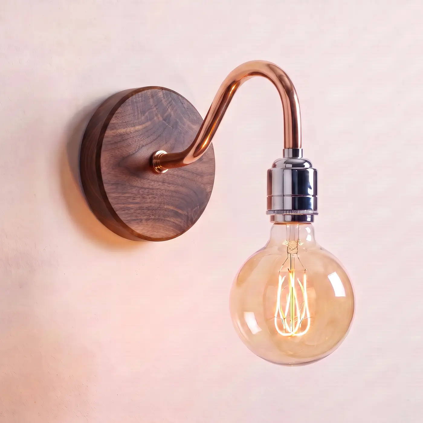 Swan neck wall light with a walnut back plate, copper swan neck arm and chrome bulb holder, lit with a globe filament bulb