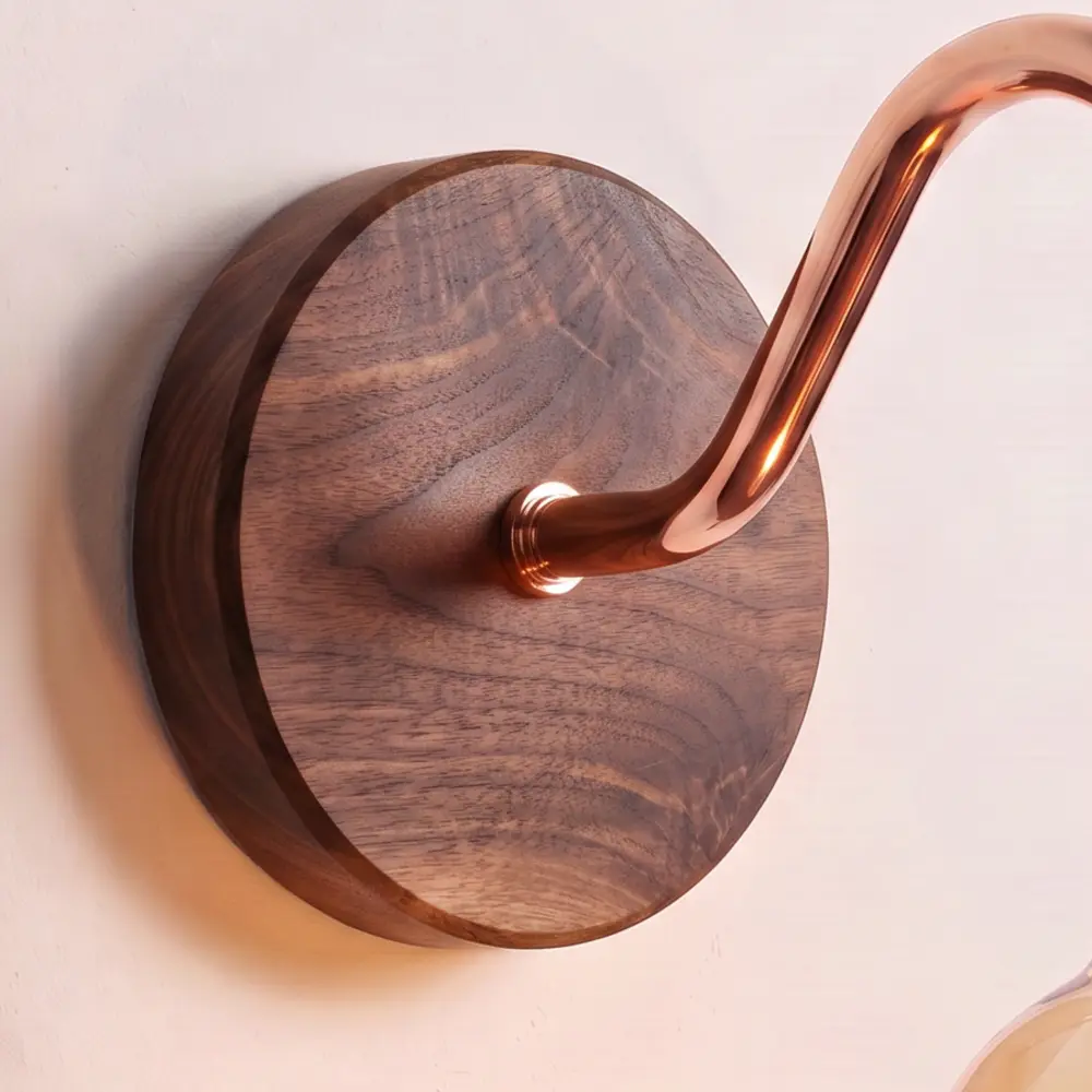 Close detail of a back plate turned from solid walnut, showing the figure in the grain, and the copper collar where the swan neck arm meets it