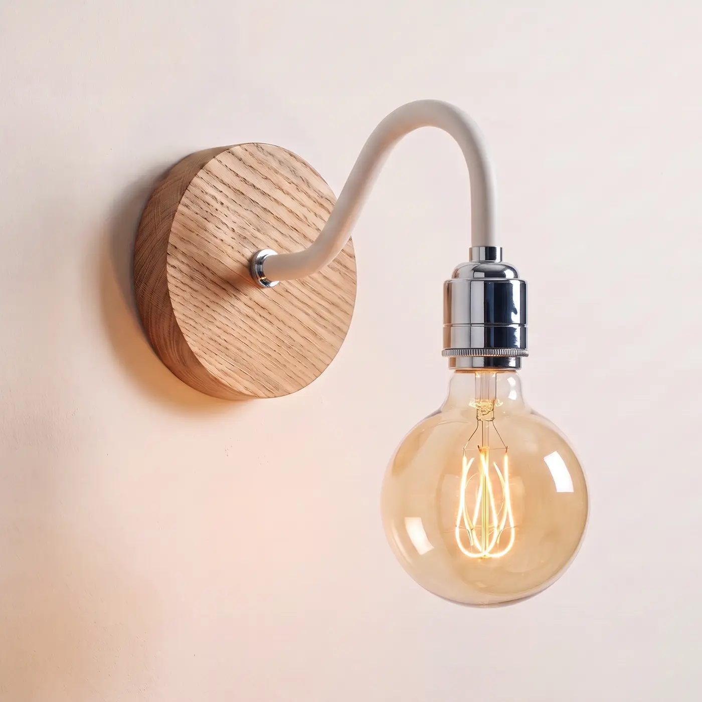 Swan neck wall light with a natural oak back plate, white swan neck arm and chrome bulb holder, lit with a globe filament bulb